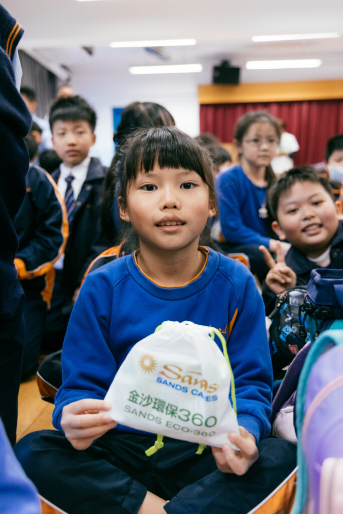 Primary school student showing her hygiene kit, with other students in the background. Green education events by Clean the World Asia, Hong Kong