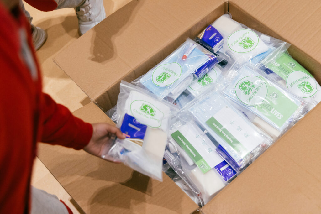 Placing completed hygiene kits in a cardboard box. Clean the World Asia charity outreach event