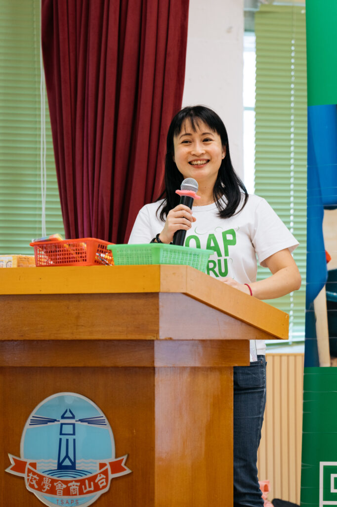 Female presenter talking at the podium • Clean the World Asia • CSR school events with Hong Kong charity
